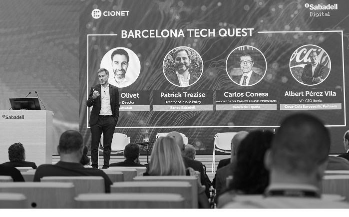 Foto de la ponencia de Roger Olivet de Banco Sabadell en la que se ven al resto de ponentes en la pantalla.